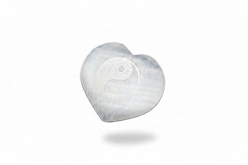 A selenite heart with a etched yin yang, on a white background