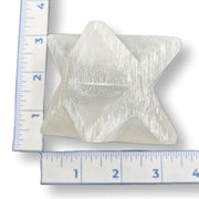 Selenite merkaba next to a ruler on a white background