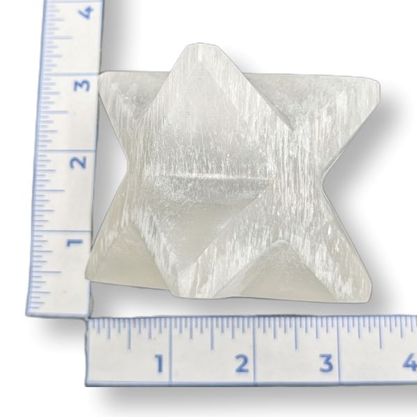 Selenite merkaba next to a ruler on a white background
