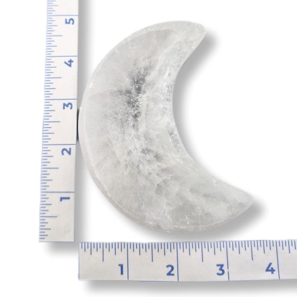 Moon-shaped stone with a ruler for scale on a white background