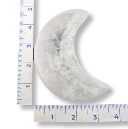 Moon-shaped stone with a ruler for scale on a white background