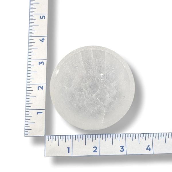 A selenite bowl with a ruler for scale on a white background
