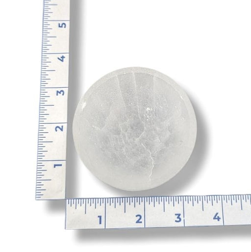 A selenite bowl with a ruler for scale on a white background