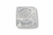 A square white selenite tray with rounded corners and a circular recessed design in the center, featuring natural gray veining, shown on a plain white background.