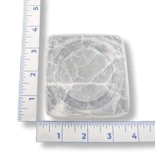 Square selenite dish with a ruler for scale on a white background