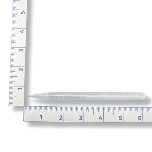 A selenite pencil wand with a ruler for measurement on a white background