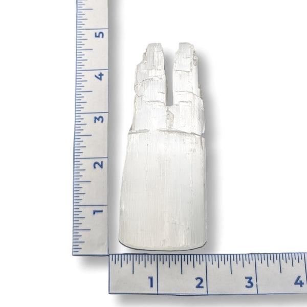 White stone sculpture with a ruler for scale on a white background