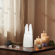 Selenite tower on a wooden surface with candles and crystals in a warm setting