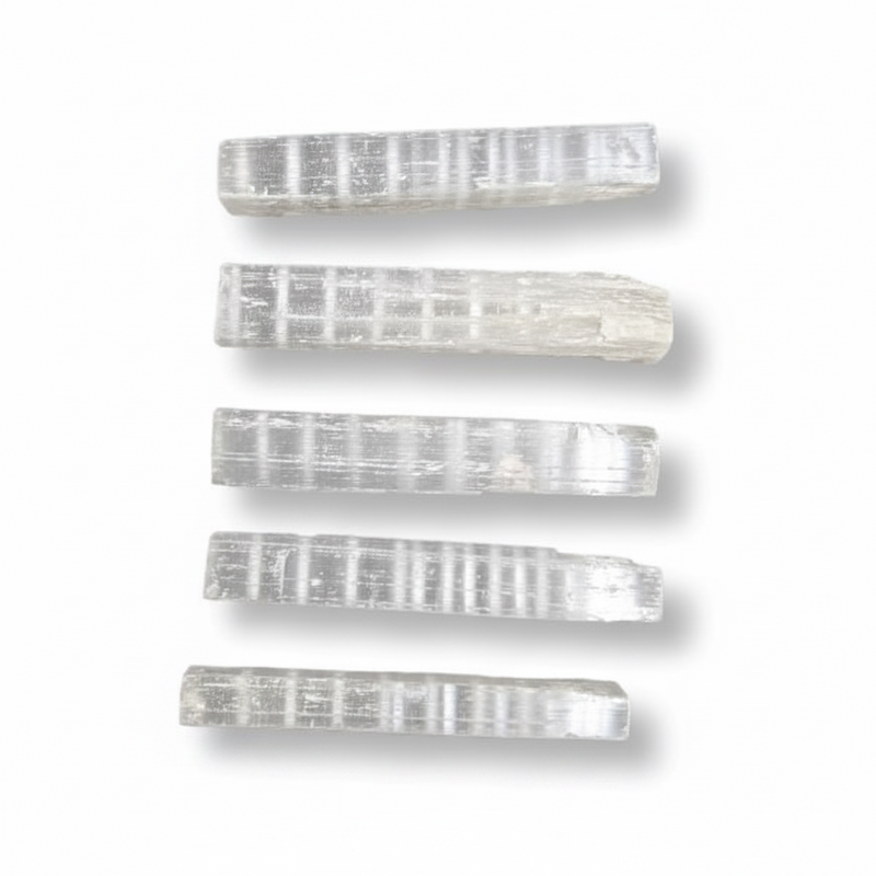 Five selenite sticks with a ribbed texture, arranged vertically on a white background with soft drop shadows.