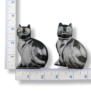 Two black onyx cats hand carved on a white background.