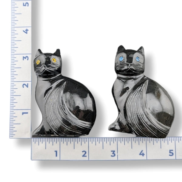 Two black onyx cats hand carved on a white background.