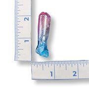 Colorful crystal next to a ruler on a white background