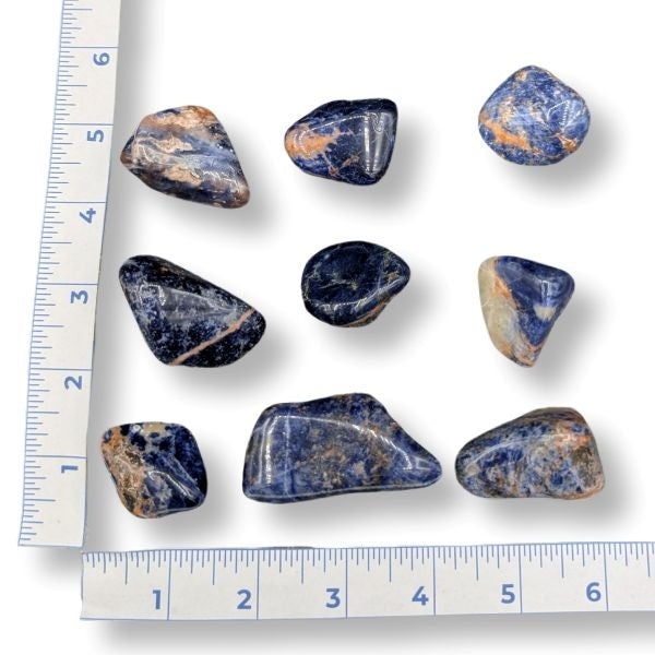 Set of blue and orange  stones with a ruler for scale on a white background