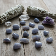 Set of blue stones, amethyst crystal, and sage on a wooden surface