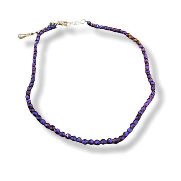A beaded anklet featuring faceted beads that shift between deep purple and blue depending on the angle, with a silver-tone clasp, shown on a white background with a soft drop shadow.