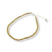 Gold beaded anklet on a white background
