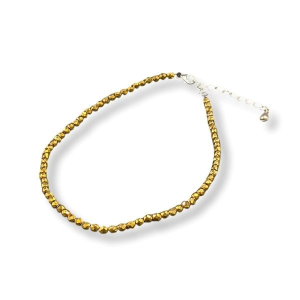 Gold beaded anklet on a white background