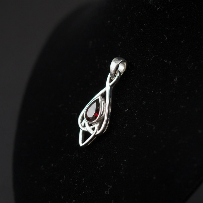 Silver pendant with a red gemstone on a black background