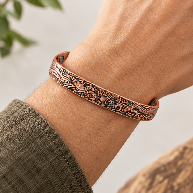 A close-up of a person's wrist wearing a copper-toned engraved bracelet with dark recessed detailing and small dark metal rivets, against a softly blurred light background.