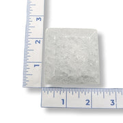 Rectangular selenite crystal with a ruler for scale on a white background