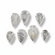 Seven raw, pointed translucent stone arrowheads with natural rough textures, arranged on a clean white background with soft drop shadows.