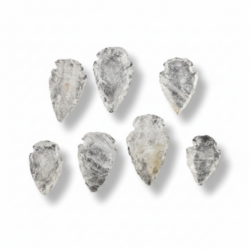 Seven raw, pointed translucent stone arrowheads with natural rough textures, arranged on a clean white background with soft drop shadows.