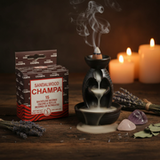 Sandalwood Champa incense packaging with an incense burner and candles on a wooden surface.