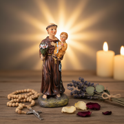 St. Anthony Statue with candles and flowers on a wooden surface