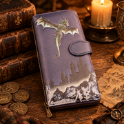 A purple zip-around wallet with an embossed dragon and castle landscape design, styled on a wooden surface with vintage books, coins, and a lit candle.