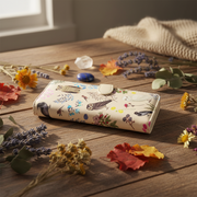 Floral-patterned wallet on a wooden surface with dried flowers and leaves