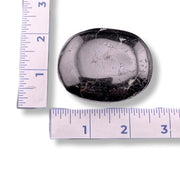 Black and white patterned stone with a ruler for scale on a white background
