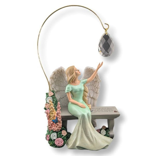 Decorative angel figurine with wings, sitting on a bench holding a crystal ball, on a white background.