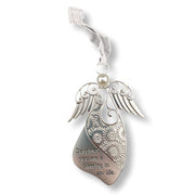 A silver metal angel ornament shaped like a winged heart pendant with floral engravings and the engraved text 'Daughter, you are a blessing in my life.' It hangs from a sheer white ribbon loop on a white background.