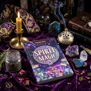 A styled flat-lay of the book 'Spirit Magic: Elements of Witchcraft' by Phoenix Leaf, surrounded by mystical props including a burning candle, an incense burner with smoke, crystals, dried flowers, and a glass jar of lavender on a purple velvet cloth.