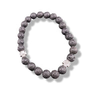 Lava stone bracelet with silver charms on a white background