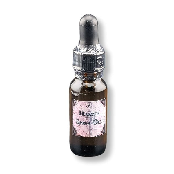 A small amber glass dropper bottle with a black rubber bulb. Featuring a pink label that reads 'Hecate Spell Oil '.