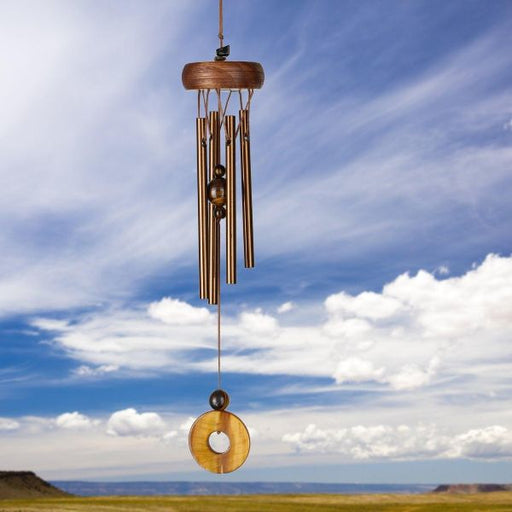 Wooden wind chime against a blue sky with clouds