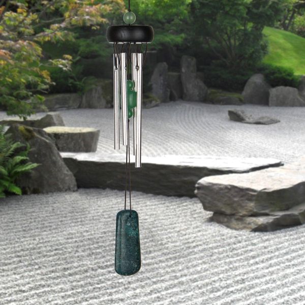 Decorative wind chime in a garden setting with rocks and greenery.