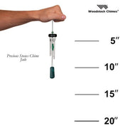 Hand holding a wind chime with measurement scale and Woodstock Chimes branding