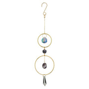 Decorative hanging ornament with gold loops, stones, and a crystal on a white background