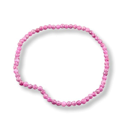 A stretch bracelet  of faceted ruby beads arranged in a loose circle on a white background.