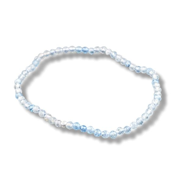 A beaded stretch bracelet made of light blue and clear faceted beads, arranged in an oval shape on a white background with a soft drop shadow.