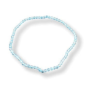 A delicate light blue beaded bracelet arranged in a loose circle on a white background with a soft drop shadow.