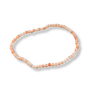 A beaded stretch bracelet made of small peach, orange, and translucent clear beads, displayed on a clean white background with a soft drop shadow.