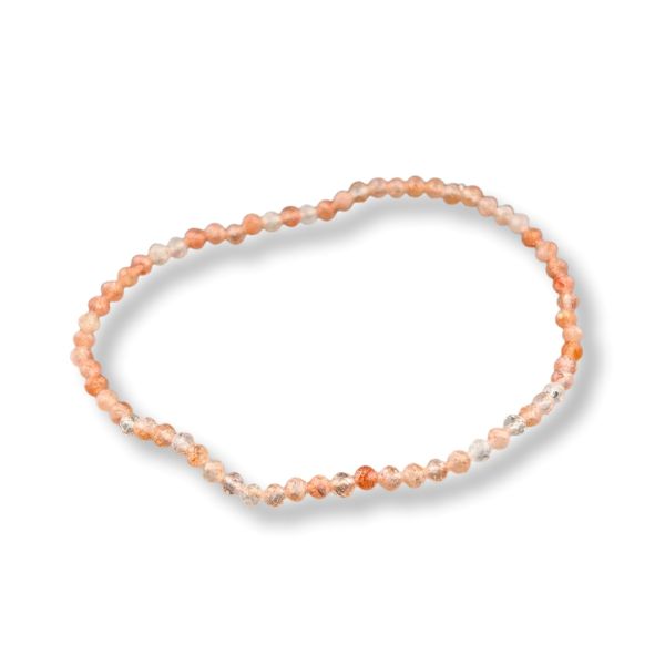 A beaded stretch bracelet made of small peach, orange, and translucent clear beads, displayed on a clean white background with a soft drop shadow.