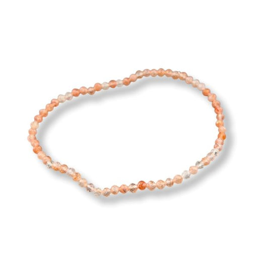 A beaded stretch bracelet made of small peach, orange, and translucent clear beads, displayed on a clean white background with a soft drop shadow.