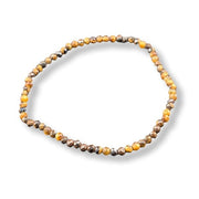 A beaded stretch bracelet made of small faceted brown and amber-orange beads, arranged in a circle on a white background.