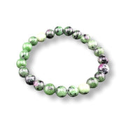 A beaded stretch bracelet made of polished round gemstone beads in green, black, white, and hints of pink, displayed on a clean white background.