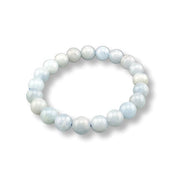 A beaded stretch bracelet made of smooth, round pearls in soft pastel shades of light blue, white, and pale gray, arranged in a circle on a white background.