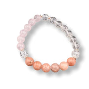 A beaded stretch bracelet featuring light pink rose quartz beads, peachy-orange quartz beads, and clear faceted crystal spacer beads, displayed on a clean white background.